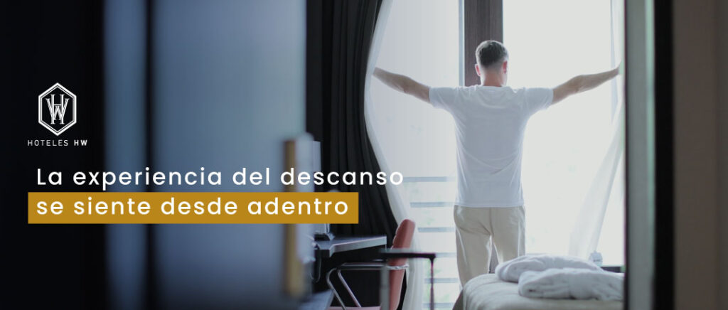 Hombre abriendo cortinas en habitación de hotel con luz natural – Hoteles HW